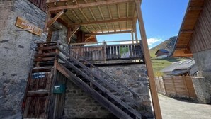 A rustic chalet with a wooden balcony, stone walls, and a sign indicating a ski lift area. - LA Ferme DU Soleil - Combles (ALBIEZ MONTROND)