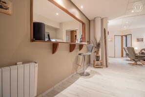 A modern interior with a large mirror, a bar stool, and a dining area with chairs and a table.