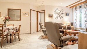 Et værelse med et spisebord til fire personer, en sofa, en stol og et lille bord med en lampe.