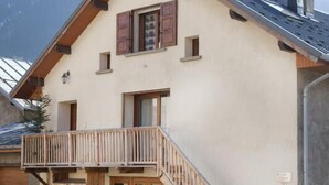 A two-story building with a balcony, wooden doors, and a staircase leading to the upper floor. - Chalet DES Alpes - Val-cenis (VAL CENIS)