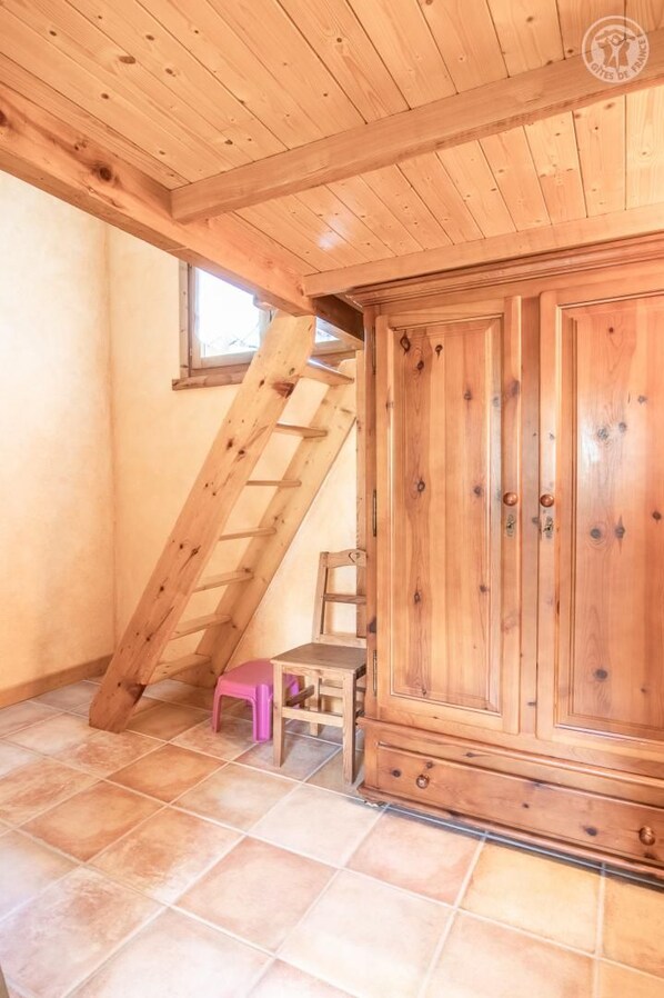 A wooden interior with a staircase, a cabinet, and a small pink chair. - LA Tour - St-martin-d'arc (ST-MARTIN-D'ARC)