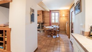 A cozy kitchen with wooden walls, a tiled floor, a dining table with chairs, and a built-in stove. - LA Tour - St-martin-d'arc (ST-MARTIN-D'ARC)