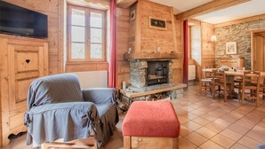 A cozy log cabin interior with a fireplace, wooden furniture, and a dining area. - LA Tour - St-martin-d'arc (ST-MARTIN-D'ARC)