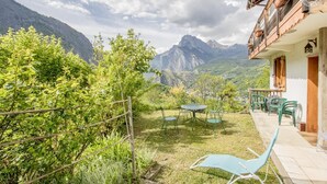 A garden with a table and chairs, a wooden fence, and a mountain view. - LA Tour - St-martin-d'arc (ST-MARTIN-D'ARC)