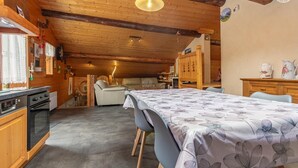 Een gezellig chalet met een eethoek, keuken en een slaapkamer op een entresol.