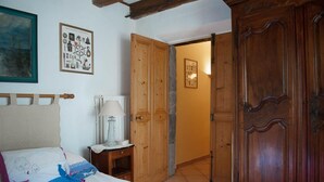 Un dormitorio con cama, mesita de noche, lámpara y armario de madera.
