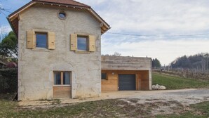 Ein rustikales Steinhaus mit geneigtem Dach, Holzhörnern und einem kleinen, runden Fenster.