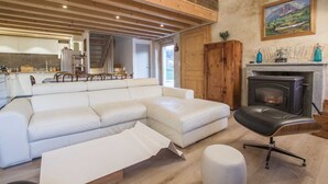 Ein modernes Wohnzimmer mit einer Eckcouch, einem schwarzen Ledersessel und einem Kamin.