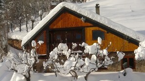 A wooden cabin with a sloped roof, surrounded by snow-covered trees and a snow-covered ground. - LES Mesanges - Jarrier (JARRIER)