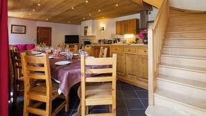 A dining area with wooden chairs and a table set for a meal, a kitchen with wooden cabinets, and a staircase. - Chez LE Marquis DU Pontet 4 (VALLOIRE)