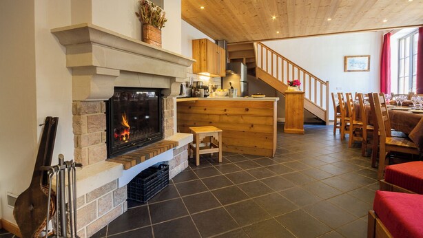 A cozy living area with a fireplace, wooden furniture, and a staircase leading to another level. - Chez LE Marquis DU Pontet 4 (VALLOIRE)