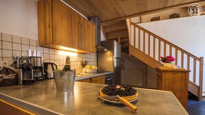 A kitchen with wooden cabinets, a stainless steel refrigerator, a coffee machine, and a bottle of champagne in a bucket. - Chez LE Marquis DU Pontet 4 (VALLOIRE)