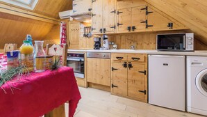 A kitchen with wooden cabinets, a microwave, a coffee maker, and a washing machine. - LA Grange Neuve - Frontenex (FRONTENEX)