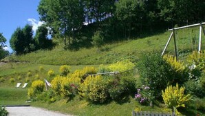 Un jardin avec une terrasse en bois, diverses plantes et une clôture en bois.