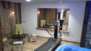 Une pièce équipée d’un tapis de course, d’un fauteuil de massage et d’un jacuzzi.