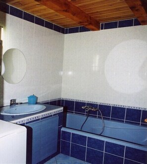 Een badkamer met een bad, een wastafel en een spiegel.
