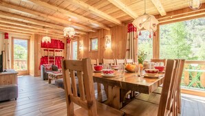 A wooden cabin interior with a dining area, wooden floors, and large windows. - LA Pastourelle 2 - Bonneval SUR ARC (BONNEVAL SUR ARC)