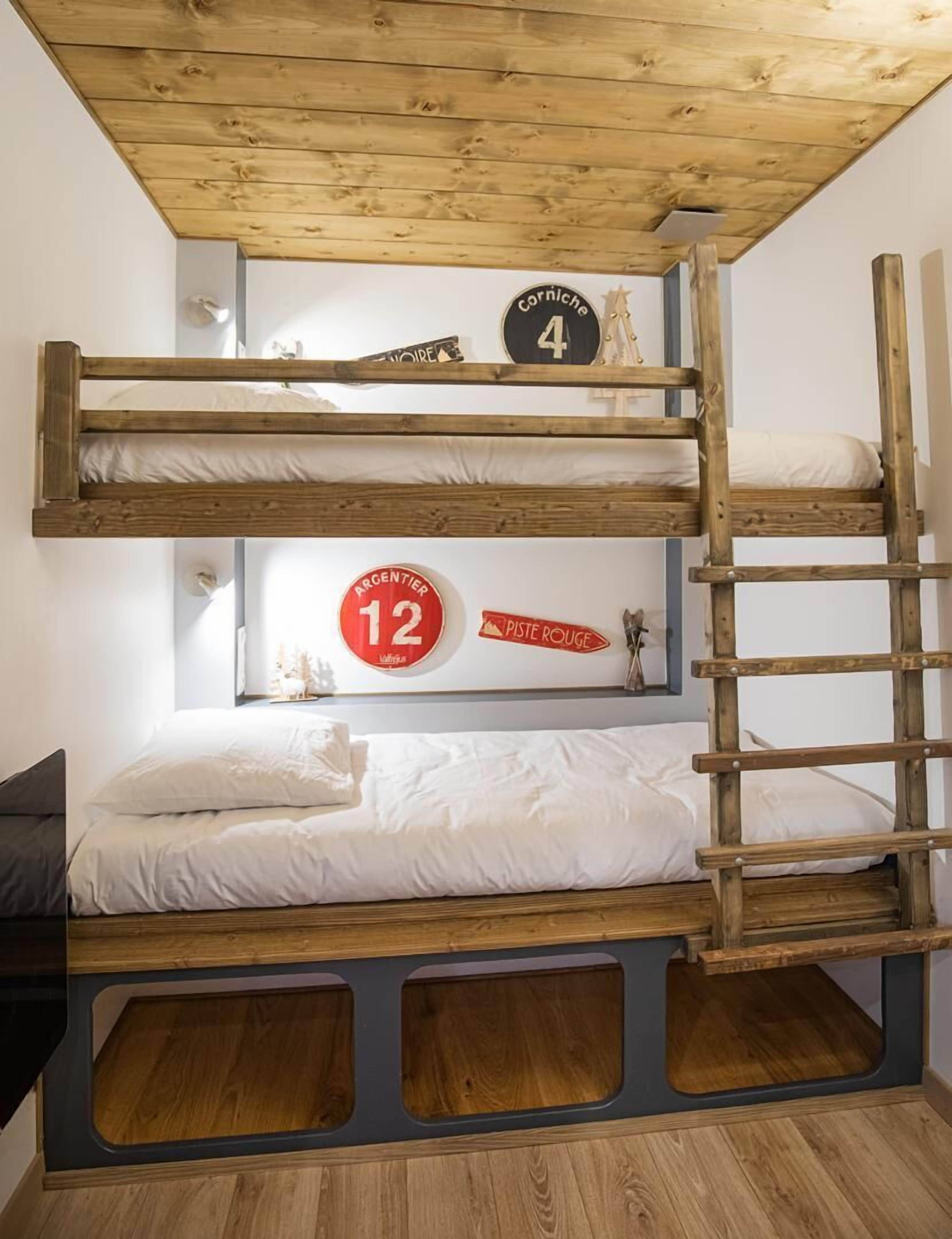A bunk bed with a wooden ladder, a small shelf, and a wall clock.