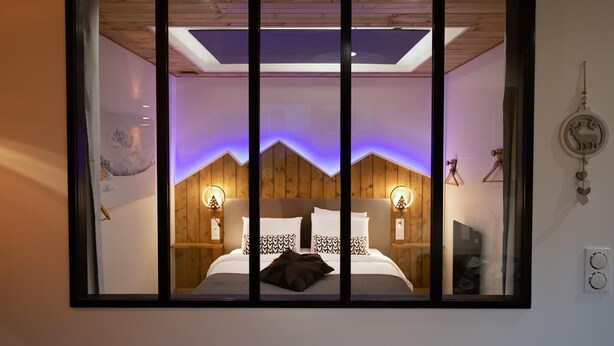 Ein Schlafzimmer mit Bett, Holzwandverkleidung, einem Oberlicht und Wandleuchten.