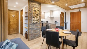 Ein modernes Wohnzimmer mit Essbereich, Holzboden und einer Steinwand.