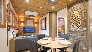 Ein modernes Wohnzimmer mit Fernseher, Sitzgelegenheiten und einer Steinwand.
