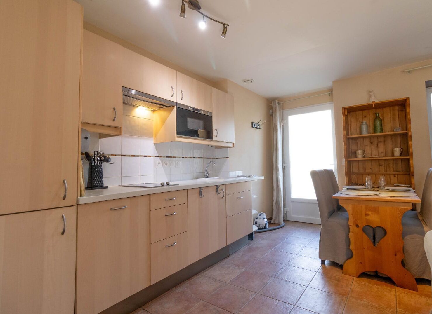 A modern kitchen with wooden cabinets, a microwave, and a dining area with a wooden table and chairs.