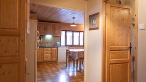 Interior de madera con cocina, comedor y un pasillo que lleva a una puerta.