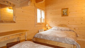 A wooden cabin bedroom with a bed, a nightstand, a lamp, and a window with curtains. - LA Verdine - Hauteluce-les-saisies (HAUTELUCE LES SAISIES)