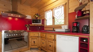A compact kitchen with wooden cabinets, a stove, a microwave, and a dishwasher. - LA Verdine - Hauteluce-les-saisies (HAUTELUCE LES SAISIES)