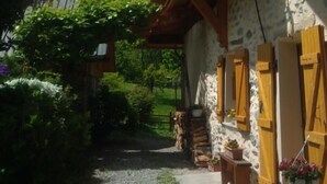 Un chalet de montagne rustique, doté d’un balcon en bois, de murs en pierre et d’un chemin de gravier menant à l’entrée.