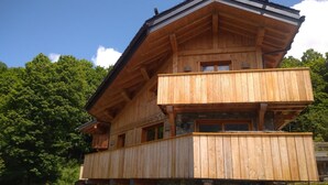 A two-story wooden cabin with a stone foundation, a balcony on the upper floor, and a stone fireplace. - Chalet Aline - Meribel-les-allues (MERIBEL LES ALLUES)