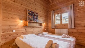 A wooden cabin room with two beds, a mural on the wall, and a window with curtains. - Chalet Aline - Meribel-les-allues (MERIBEL LES ALLUES)