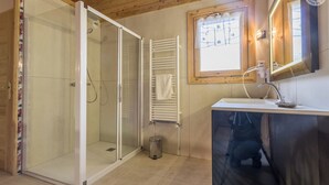 A bathroom with a glass shower enclosure, a white sink with a modern faucet, and a window with a wooden frame. - Chalet Aline - Meribel-les-allues (MERIBEL LES ALLUES)