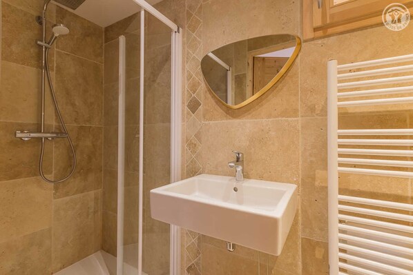 Un baño con ducha, lavabo y toallero.