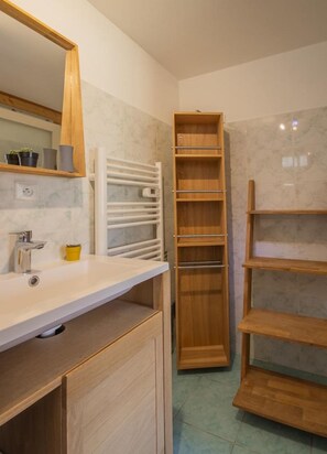 A bathroom with a white sink, wooden cabinets, a mirror, and a white towel rack.