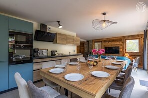 A modern kitchen with a built-in oven and a dining area with a wooden table set for six.