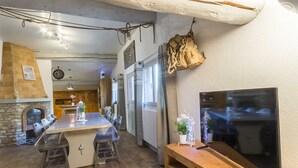 A kitchen with a central island, wooden flooring, a stone fireplace, and a mounted flat-screen TV. - LE Boujou - Hauteluce-les-saisies (HAUTELUCE LES SAISIES)