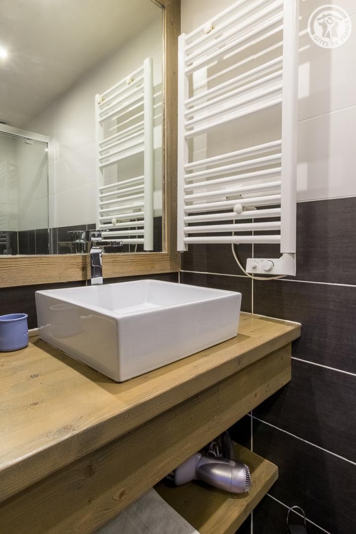 Un baño con un lavamanos blanco, encimera de madera y un espejo.