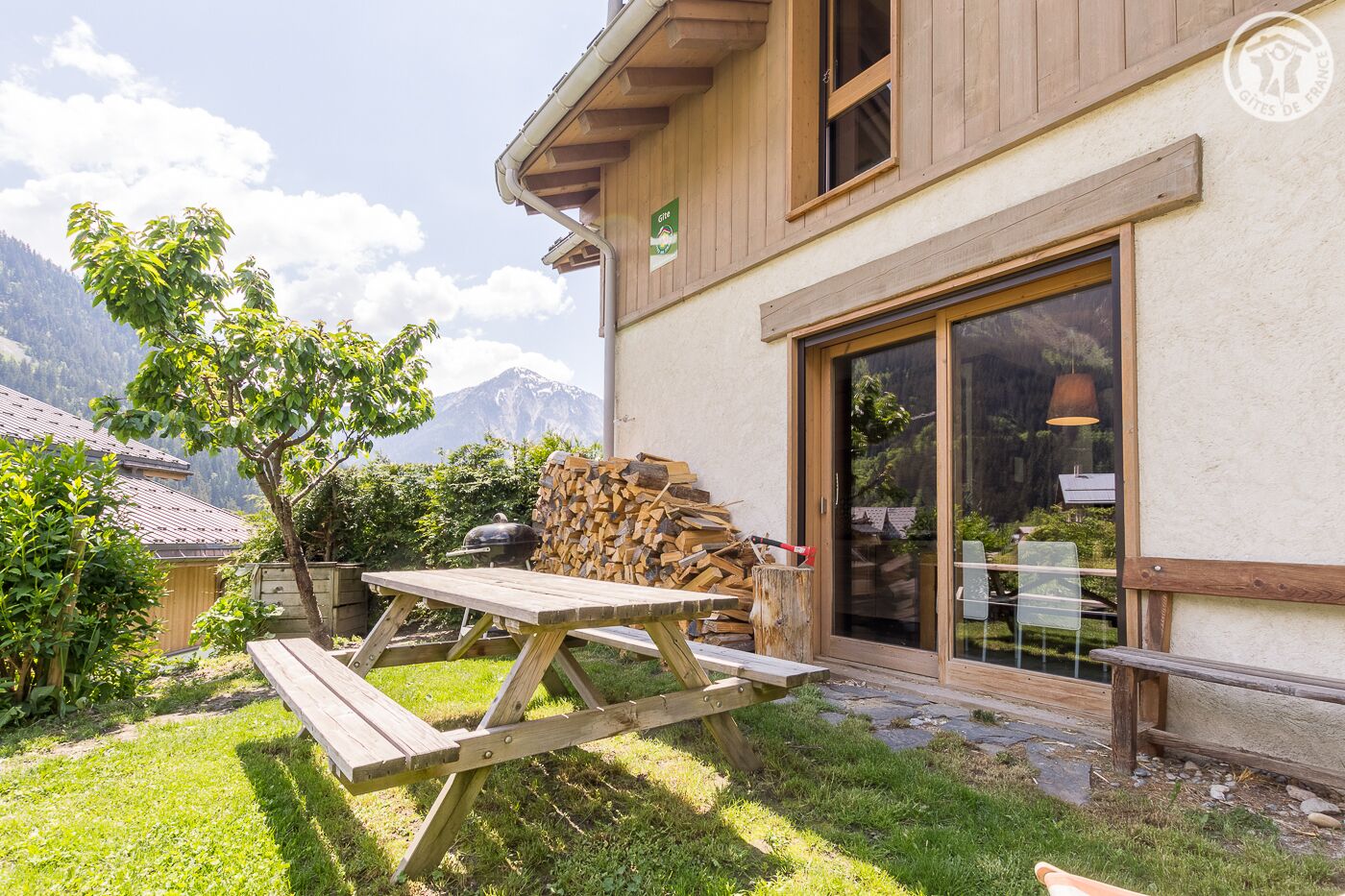 Une maison en bois avec un patio, un barbecue et une vue sur la montagne.