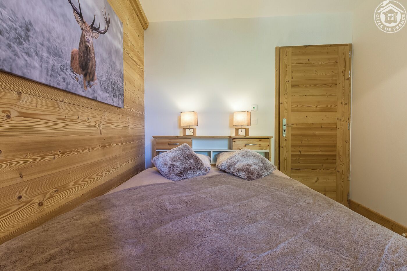 Ein Schlafzimmer mit einem hölzernen Kopfende, einem Bett mit einer flauschigen Decke, zwei Nachttischlampen und einem Holzschrank.