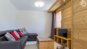 A modern living room with a grey sofa, a wooden coffee table, and a television on a wooden stand. - LA Louve - Hauteluce-les-saisies (HAUTELUCE LES SAISIES)