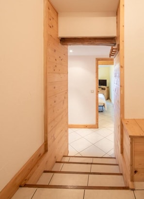 A narrow wooden staircase leading to a room with a bed and a television.