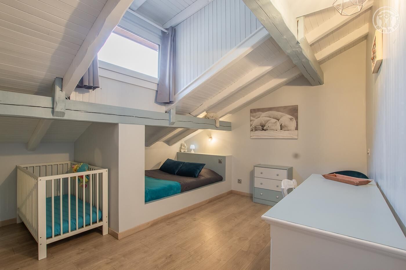 Quarto de criança com beliches, berço, escrivaninha e janela.