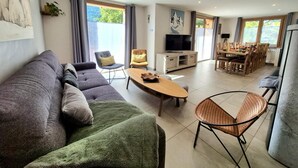 Ein modernes Wohnzimmer mit einer Couch, einem Couchtisch und einem Essbereich mit Stühlen und einem Fernseher.