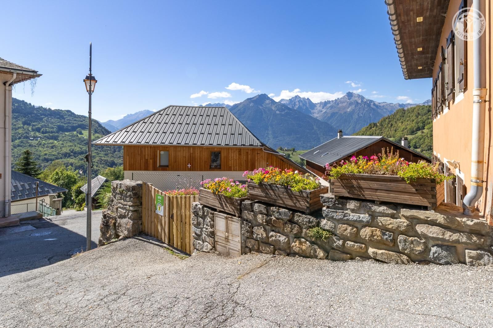 A rustic mountain village with stone walls, wooden buildings, and flower boxes.