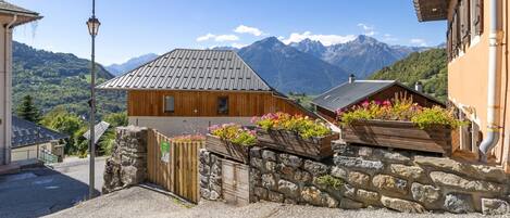 A rustic mountain village with stone walls, wooden buildings, and flower boxes.