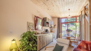 Una cocina acogedora con armarios de madera, un comedor con mesa y sillas, y un amplio ventanal con vistas al exterior.