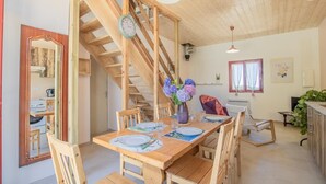 Un comedor de madera con escalera, un reloj y un florero con flores.