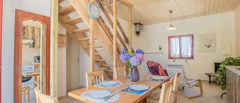 A wooden dining area with a staircase, a clock, and a vase with flowers.