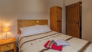 Una cama bien hecha con cabecera de madera, una lámpara de noche y un armario.